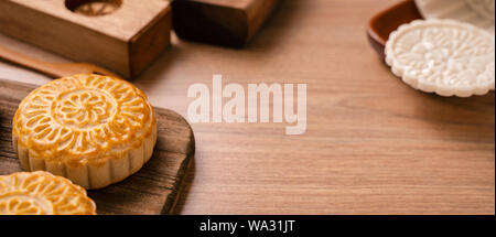 Una forma rotonda sfornato fresco torta della luna - pasticceria Cinese per moonckae Mid-Autumn Festival di luna su sfondo di legno e serve il vassoio, close up, spazio di copia Foto Stock