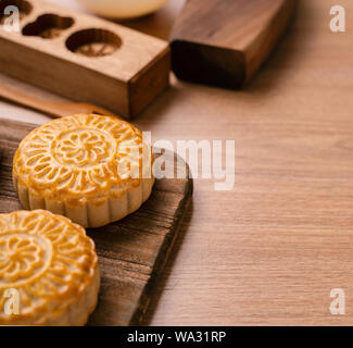 Una forma rotonda sfornato fresco torta della luna - pasticceria Cinese per moonckae Mid-Autumn Festival di luna su sfondo di legno e serve il vassoio, close up, spazio di copia Foto Stock