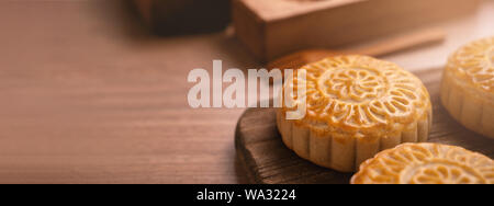 Una forma rotonda sfornato fresco torta della luna - pasticceria Cinese per moonckae Mid-Autumn Festival di luna su sfondo di legno e serve il vassoio, close up, spazio di copia Foto Stock