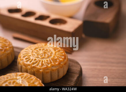 Una forma rotonda sfornato fresco torta della luna - pasticceria Cinese per moonckae Mid-Autumn Festival di luna su sfondo di legno e serve il vassoio, close up, spazio di copia Foto Stock