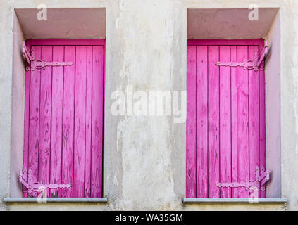 Le finestre di casa di villaggio con persiane di colore rosa Foto Stock