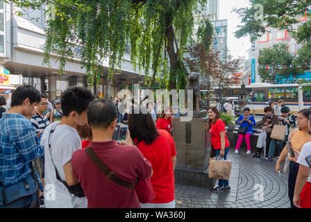 Turisti asiatici thaking una foto accanto Chuken Hachiko, una famosa statua di un cane fedele, Shibuya, Tokyo, Giappone Foto Stock