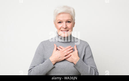 Tipo senior donna mantenendo entrambi i palmi sul petto Foto Stock