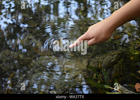 Close-up di donna mano teneramente toccando, contraendo pulito fresco di acqua dolce/Turismo, uno stile di vita attivo, natura e problemi di inquinamento del concetto. Foto Stock