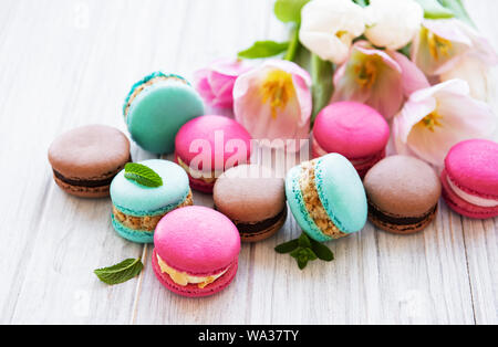 Amaretti colorati e tulipani su un marmo bianco sullo sfondo Foto Stock