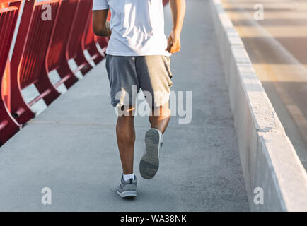 Sporty afro corpo uomo correre giù il ponte Foto Stock