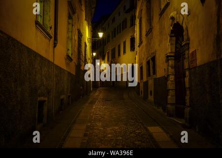 Vicolo nel mezzo di edifici con luci di strada illuminate di notte Foto Stock