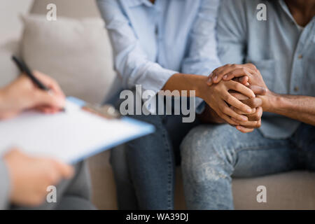 Nero il marito e la moglie tenendo le mani a psicologo coniugale dell'ufficio Foto Stock