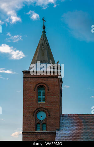 Chiesa in Guelpe, Germania con due cicogne allevamento su la torre dell orologio tetto Foto Stock