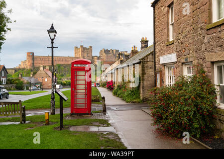 Bamburgh village, casella Telefono e castello, Northumberland, England, Regno Unito Foto Stock