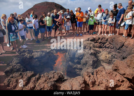 TIMANFAYA, Spagna - 13 agosto: turisti osservare una dimostrazione di calore vulcanico a visitatori cente su 13 Agosto 2019 nel Parco Nazionale di Timanfaya, Spagna Foto Stock