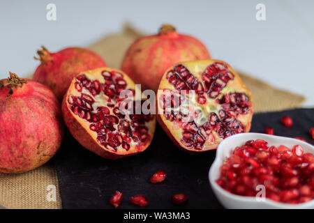 In questa foto si può vedere una vita ancora di più pezzi di melograno frutto di un intenso colore rosso su una piastra di ardesia. È un frutto che può essere cons Foto Stock