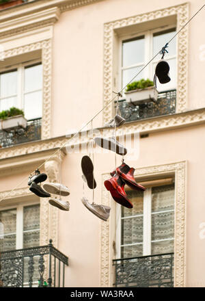 Mostra appesa per i loro lacci delle scarpe dalla linea tra edifici di appartamenti. Il quartiere di Marais, Parigi, Francia Foto Stock