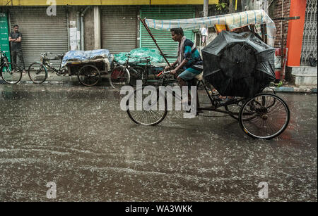 Kolkata, India. 17 Ago, 2019. Un uomo che cavalca un rickshaw in heavy rain in Kolkata, India, Agosto 17, 2019. Credito: Tumpa Mondal/Xinhua/Alamy Live News Foto Stock