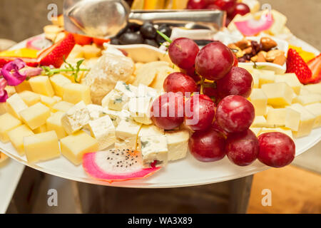 Frutta fresca fragole, uva e pitaya su spiedini con vari formaggi morsi - solo boccone che serve - disposti party finger food Foto Stock
