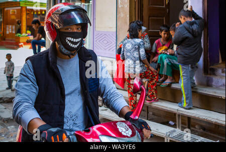 Kathmandu, Nepal  Novembre 02,2017: giovane uomo asiatico su una moto con un divertente di protezione della respirazione intorno al suo volto Foto Stock