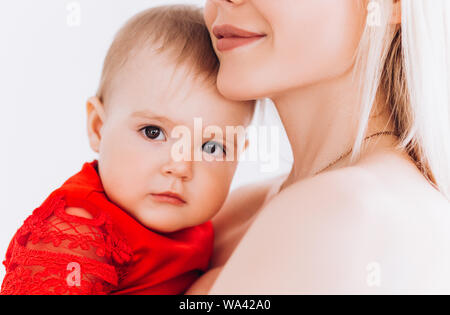 Nizza, famiglia, buona foto di madre e figlia in abiti rossi in studio. Giornata della madre e le sue figlie. Foto Stock