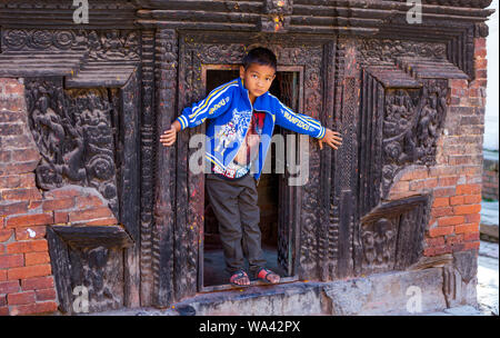 Kathmandu, Nepal-November 03,2017: giovane serio cerca ragazzo asiatico presenta orgogliosamente se stesso durante la riproduzione di un tempio Foto Stock