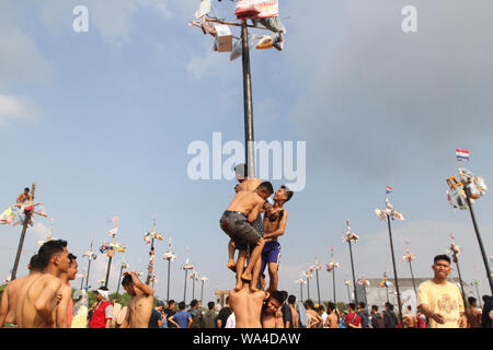 I partecipanti che lottano per salire poli grassa durante panjat pinang, un polo concorso di arrampicata per celebrare l'Indipendenza Indonesiana giorno del 74º anniversario. Foto Stock