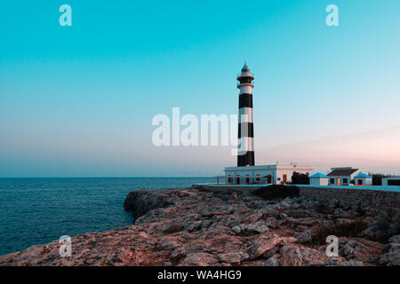 Il cappuccio Artrutx faro sul mediterraneo spagnolo isola di Minorca. Teal e vista arancione Foto Stock