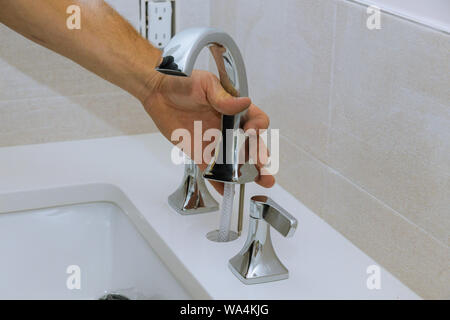 Plumber Installazione rubinetto di acqua in bagno a lavorare in una stanza da bagno Foto Stock