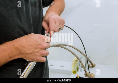 Installazione di chrome rubinetto idraulico al lavoro in un bagno plumbing assemblare il servizio di riparazione Foto Stock