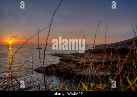 Il tramonto sotto il bel cielo azzurro sulla spiaggia Foto Stock