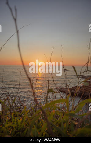 Il tramonto sotto il bel cielo azzurro sulla spiaggia Foto Stock