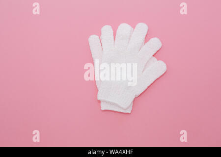 Donna massaggio esfoliante con guanto per doccia su sfondo rosa.i guanti per uso nella doccia per massaggio e scrub. La bellezza dello sfondo con cosmetic prod Foto Stock