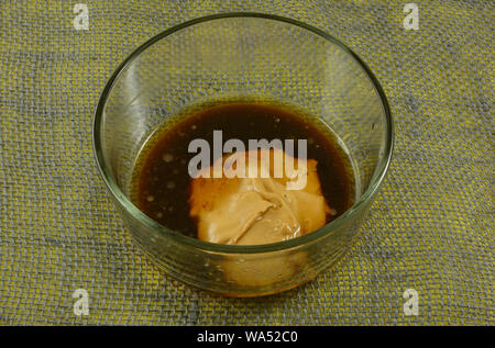 Rendendo con salsa di burro di arachidi con salsa di soia e olio di sesamo e il succo di zenzero in recipiente di vetro Foto Stock