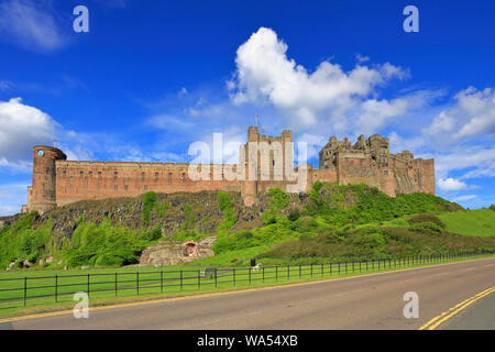 Il castello di Bamburgh dalla strada del Northumberland sentiero costiero, Bamburgh, Northumberland, Inghilterra, Regno Unito. Foto Stock