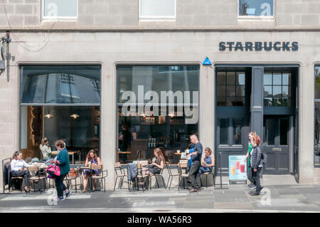 Le persone sedute a bere caffè al di fuori di un ramo di Starbucks in Upperkirkgate, Aberdeen. Foto Stock