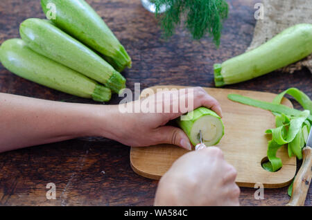 La donna è il carving le zucchine in cucina. Foto Stock