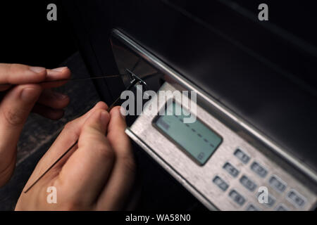 Close-up del ladro con le mani in mano il tentativo di rompere Home denaro sicuro ed eseguire rapina. La sicurezza e la protezione della casa concetti. Foto Stock