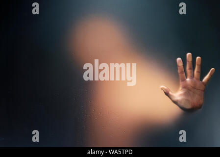 Creepy man tenendo premuto il vetro smerigliato con una sola mano. Foto Stock