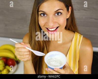 Ragazza luce mangiare lo yogurt a casa. Chiudere dall'alto. Un sano concetto. Foto Stock