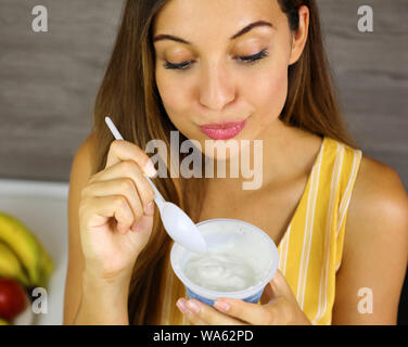 Bella giovane donna luce mangiare lo yogurt greco a casa. Chiudere dall'alto. Un sano concetto. Foto Stock