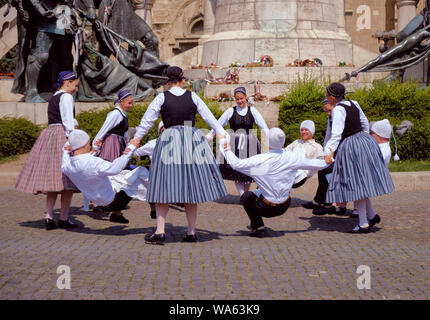 Tradizionale ungherese truppa di danza in costumi folkloristici con una esecuzione pubblica in piazza. Danza in cerchio con l'uomo facendo calcoli danza. Foto Stock