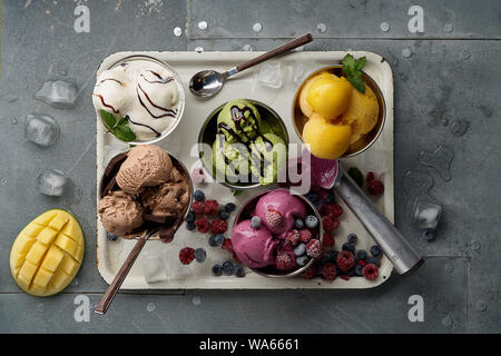 Un assortimento di sapori e colori di gourmet gelato italiano servito sul tavolo in acciaio. Mango, cioccolato, Verde matcha ice cream Foto Stock