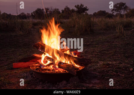 Campfire al crepuscolo di bruciare nel romantico paesaggio della savana vicino l'Okavango, Namibia, Africa Foto Stock