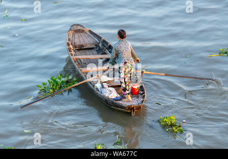 Traghetto di canottaggio donna porta i visitatori o i prodotti agricoli sul fiume mercato galleggiante , questo è il trasporto principale il nuovo anno lunare in Soc Trang, Foto Stock