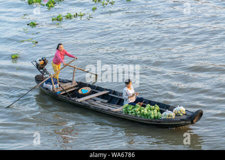 Traghetto di canottaggio donna porta i visitatori o i prodotti agricoli sul fiume mercato galleggiante , questo è il trasporto principale il nuovo anno lunare in Soc Trang, Foto Stock