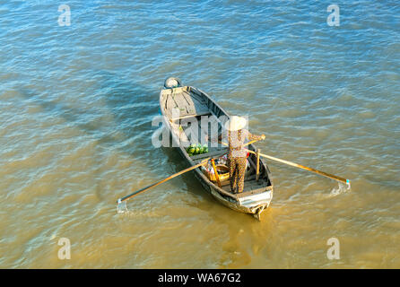 Traghetto di canottaggio donna porta i visitatori o i prodotti agricoli sul fiume mercato galleggiante , questo è il trasporto principale il nuovo anno lunare in Soc Trang, Foto Stock