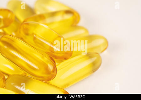Pila di colore oro di olio di pesce capsule isolati su sfondo bianco vista. Pesce salmone capsule vista. Omega 3. La vitamina E. supplementari di cibo buono per hea Foto Stock