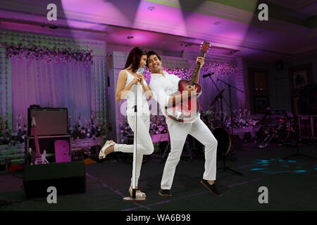 Young woman singing and young man playing a guitar together Stock Photo