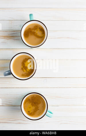 Masala tea in tazze di ceramica con l'inverno spezie di cannella e zenzero su una luce sullo sfondo di legno vista superiore con copyspace Foto Stock