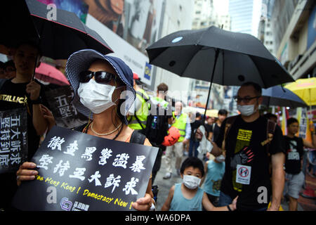 Hong Kong, Cina. Il 18 agosto 2019. Una donna cammina con una maschera e un segno "Libera Hong Kong! La democrazia adesso!' attraverso una strada commerciale a una protesta nel rally di Victoria Park. Foto: Gregor Fischer/dpa Credito: dpa picture alliance/Alamy Live News Foto Stock