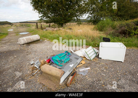 Un esempio di fly-ribaltamento accanto a una strada di campagna nel Dorset. Gli elementi includono un televisore a schermo piatto, una sedia e zaino. Il Dorset England Regno Unito GB Foto Stock