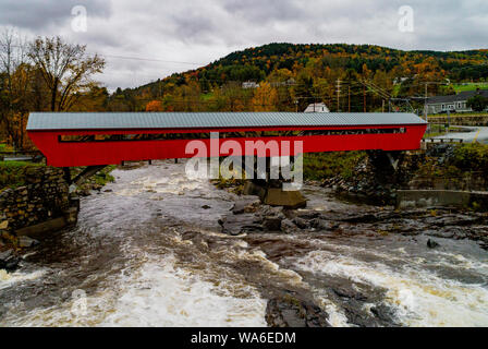 Un rosso ponte coperto costruito una prima volta nel 1883 si estende rapidamente un fiume che scorre nel Vermont Foto Stock