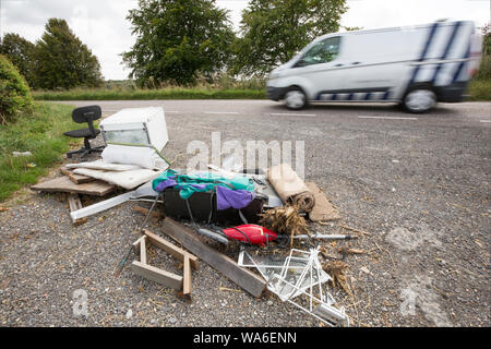 Un veicolo in transito di rifiuti oggetto di dumping accanto a una strada di campagna nel Dorset. Gli elementi includono un televisore a schermo piatto, una sedia e zaino. Il Dorset England Regno Unito GB Foto Stock